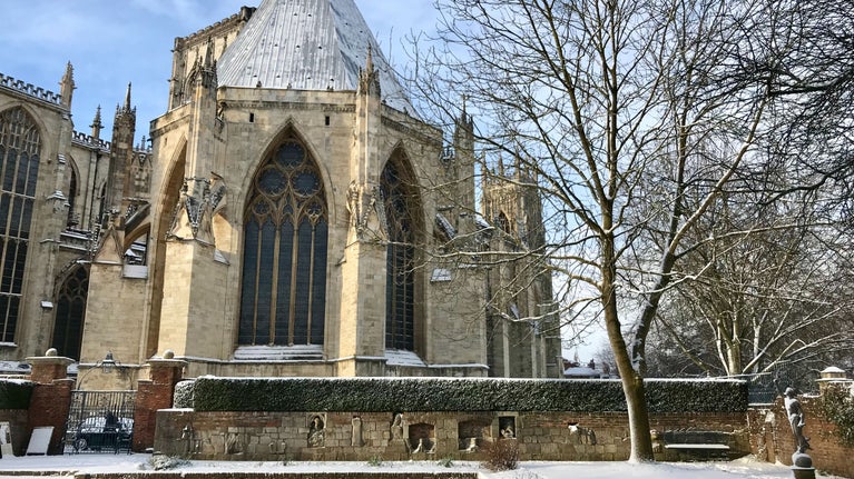 Snowy garden looking towards part of a grand Minster building